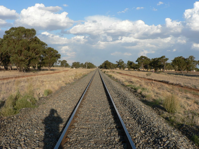 The view looking east through the former station location. The possible remains of the platform are a mound on the right in the middle distance.