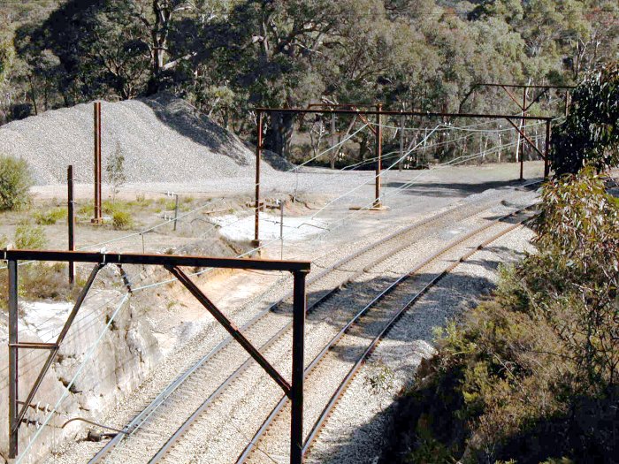 The view looking down over the location.  The up platform was where the short cutting is directly behind the stanchion.  There was a similar platform opposite.  In the background can be seen the remains of the short goods platform.