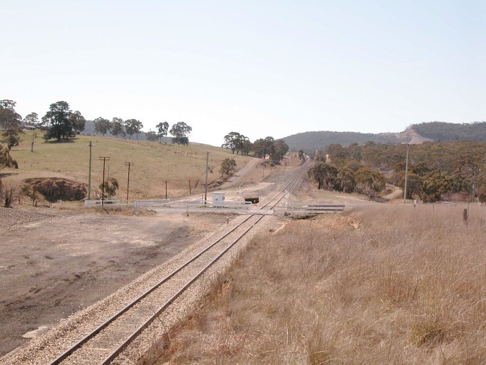 The view looking down at the one-time station location, on the far side of the crossing. No trace remains of the former turntable, which was located in the flat area in the left foreground.