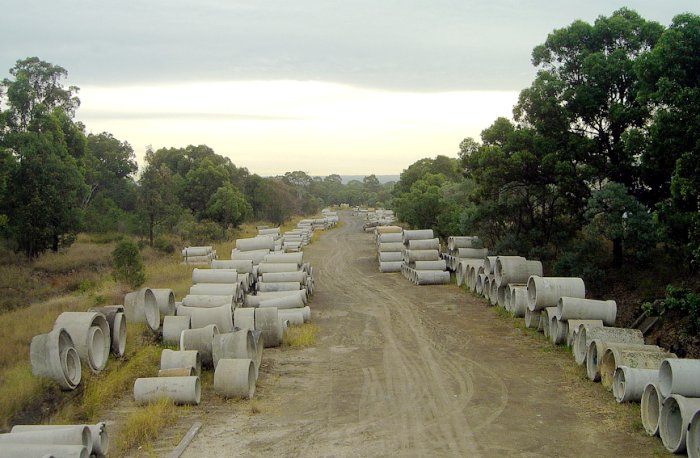 The view looking west from the footbridge revels the former yard is now used to store concrete pipes.