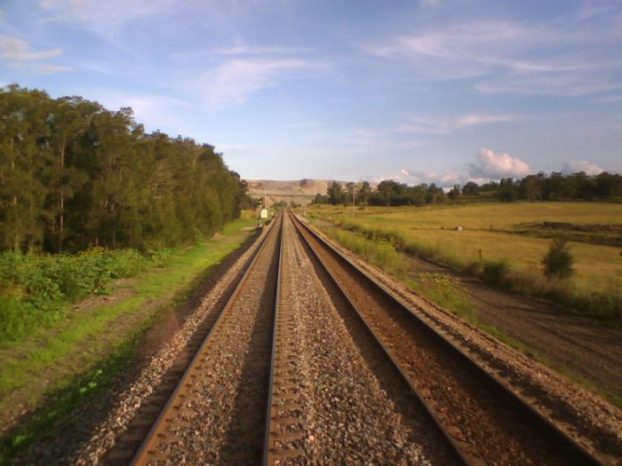 The view looking in the down direction towards the location of the former station, in the vicinity of the tonnage signal. The original alignment used to travel in a straight line up the hill through the middle of the mine.